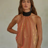 Woman wearing the Eos Halter Top in sheer golden-rose fabric with black ribbon halter tie, photographed against a neutral background.