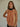 Woman wearing the Eos Halter Top in sheer golden-rose fabric with black ribbon halter tie, photographed against a neutral background.