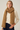 Woman wearing the Eto Pashmina in warm camel chunky knit wool, soft neutral background, cozy editorial style – Matte.
