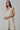 Model wearing natural linen Ezeiza Dress with fringed V-neckline.