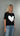 Woman wearing a black t-shirt with a white heart design on a gray background