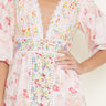 Woman wearing a floral dress with a plain background close up