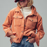 Front view of the Genova corduroy jacket styled open with a white mock-neck top, blue jeans, and a burgundy baseball cap, highlighting the oversized fit and flap chest pockets..