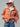Front view of the Genova corduroy jacket styled open with a white mock-neck top, blue jeans, and a burgundy baseball cap, highlighting the oversized fit and flap chest pockets..