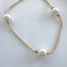 A gold-plated bracelet with white pearls and gold beads, displayed against a white background.