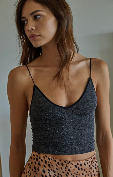 Model wearing the Glenn Top — black sparkly ribbed shoulder-strap knit top with V-neckline, styled with printed skirt for a soft neutral look.