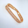 Gold double row bracelet with polished beads and cubic zirconia stones on white background