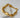 Gold bracelet with irregular organic-shaped beads and small round spacers displayed on white stone background