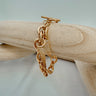 Gold chunky chain bracelet with textured lightning bolt charm displayed on wooden jewelry stand