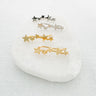 Set of gold and silver star-shaped climber stud earrings on white marble crystal surface