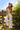 woman outdoors wearing Golden Star Wide-Leg Pants, ivory fabric with gold star embroidery, styled with matching vest and wide-brim hat, boho resort look
