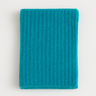 Hono Scarf in turquoise ribbed knit, soft textured scarf folded flat on beige background.