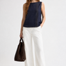 Woman wearing the Hotflix navy denim sleeveless top with white wide-leg pants and a brown handbag.