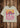 Humboldt Tee — white cotton t-shirt with vibrant retro sunset and cactus print in pink, orange, and purple tones, hanging on wooden background.