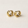 Iris Huggie Earrings small gold-toned huggie earrings shown side by side on fabric background.