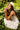 "back view of woman wearing ivory midi dress with gold star embroidery, adjustable tie straps, tiered skirt, summer resort fashion"