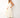 "side view of woman wearing ivory midi dress with gold star embroidery, v-neck, spaghetti straps, tiered skirt, tan sandals, summer resort style"