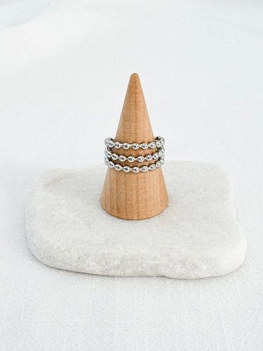 A gold-plated silver beaded ring displayed on a wooden stand with a white cushion