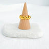 Gold-plated twisted heart sculptural ring displayed on wooden cone over marble base