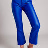 Model wearing cobalt blue slim pants with coated finish and white top — modern city look.
