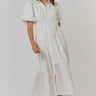 A model wearing a white short-sleeved dress with a button-down front and a flattering waist tie.