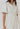 Model wearing white Lariatt Dress with puff sleeves, waist tie, and button-down front.