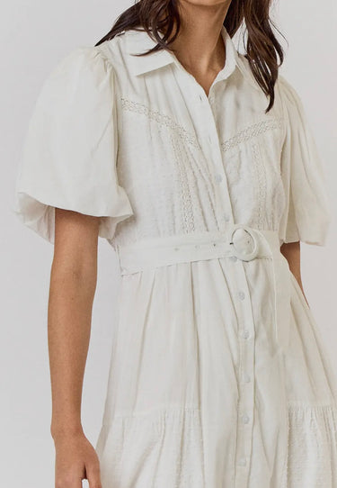 Model wearing white Lariatt Dress with puff sleeves, waist tie, and button-down front.