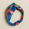 Leaves Turban Headband — colorful tropical print fabric headband with twisted turban detail, displayed on beige background.