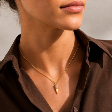 Model wearing the Lenat Necklace with a gold crystal spike pendant layered over an open-collar blouse for an elegant everyday look.