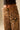Leopard print pants with a brown belt on a neutral background