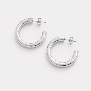 Lorenza Hoop Earrings featuring polished silver-plated classic hoop earrings with a smooth rounded silhouette, mirror finish, secure hinged closure, lightweight design, and timeless everyday style, displayed on a soft white background.