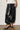 Woman wearing Lumit black balloon pants featuring a relaxed silhouette, elastic waistband, gathered ankle hem, and a lustrous finish.