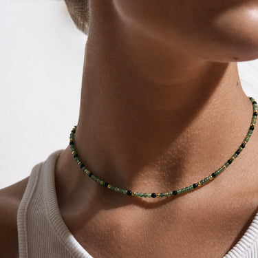 Lunne Necklace worn on model showing short green beaded necklace styled at collarbone with layered jewelry look.