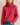 Woman wearing a bright pink turtleneck sweater against a beige background
