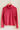 Pink turtleneck sweater on a wooden hanger against a beige wall
