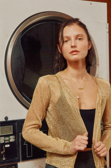 Close-up portrait of the Mats Metallic Cardigan highlighting the champagne gold shimmer knit, open-front silhouette, and elegant lightweight texture.