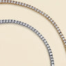 Mika Necklace luxury tennis necklace with brilliant simulated diamonds in gold and silver finishes on neutral background.