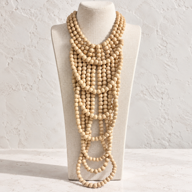 Milat multi-strand neutral beaded statement necklace featuring layered ivory toned strands displayed on a white jewelry bust.