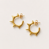 Millan Hoop Earrings featuring polished gold-plated hoop earrings with sculptural starburst edges, a rounded open-hoop silhouette, smooth mirror finish, secure post-back closure, lightweight design, and modern statement style.