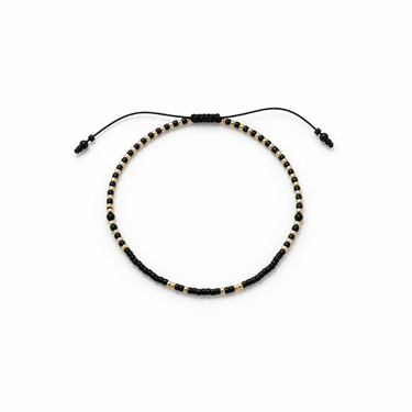Mimot Bracelet flat lay showing fine gold and small black beads and sliding adjustable closure