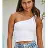 Model wearing the Minuett Top in white featuring a fitted ribbed knit construction, asymmetrical one-shoulder neckline, and cropped silhouette, paired with light-wash denim jeans.