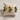 Minutti Bracelet in olive green featuring glossy round beads and slim gold-tone bars in a sculptural multi-row design displayed on a cream jewelry cushion.