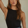 Model wearing the black Montauk Top with a ribbed knit texture, sleeveless fitted silhouette, cropped length, and elegant satin skirt for a modern everyday look.