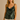 Woman wearing a green velvet tank top against a beige background
