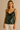 Woman wearing a green velvet tank top against a beige background