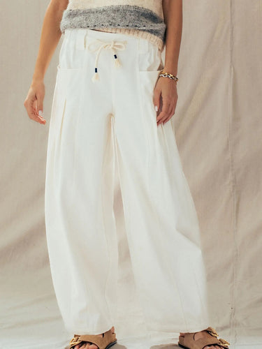 Close-up of the Mora drawstring pants showing the adjustable waistband, oversized patch pockets, and soft draping fabric.
