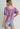 Model wearing the Nimes Top — lilac short-sleeve blouse with square neckline, puff sleeves, and textured stitching, styled with denim shorts for a soft bohemian look.