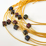 Noir & Gold Pavé Necklace by Matte, gold chain with cube pavé gemstones in purple, green, and blue on white background