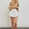 Model wearing white frayed short with drawstring waist and sneakers — casual summer look.
