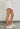 Model wearing white frayed short with drawstring waist and sneakers — casual summer look, side view.